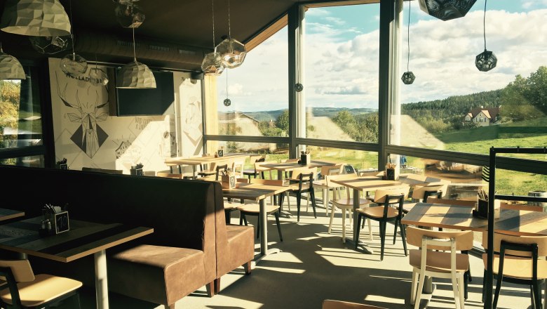 Innenansicht der Wexl Lounge mit großen Fenstern und Blick auf die Landschaft.