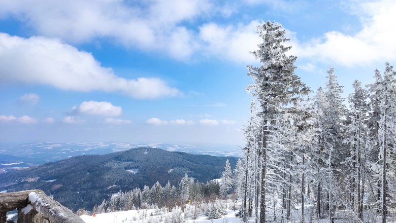 Verschneite Berglandschaft mit B&auml;umen und blauem Himmel.