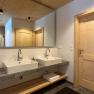 Modernes Badezimmer mit zwei Waschbecken, Holzdecke und -türen.