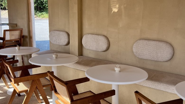 Innenbereich eines Caf&eacute;s mit Holzm&ouml;beln und runden Tischen.