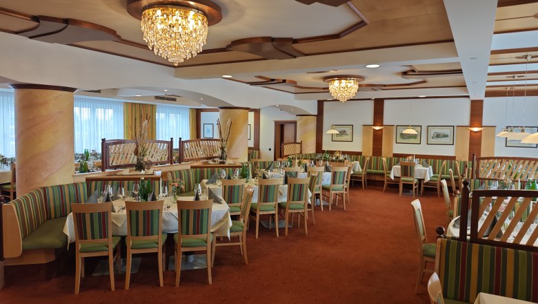 Eleganter Speisesaal mit Kronleuchtern und gedeckten Tischen im Hotel Thier.