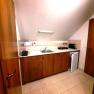 Kleine K&uuml;chenzeile mit Holzschr&auml;nken, Sp&uuml;le, Toaster, Wasserkocher und Mini-K&uuml;hlschrank unter einer Dachschr&auml;ge.