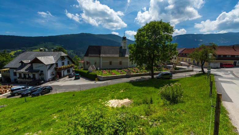 L&auml;ndliche Szene mit Kirche, Gasthaus und gr&uuml;ner Wiese in Aspangberg-St. Peter.