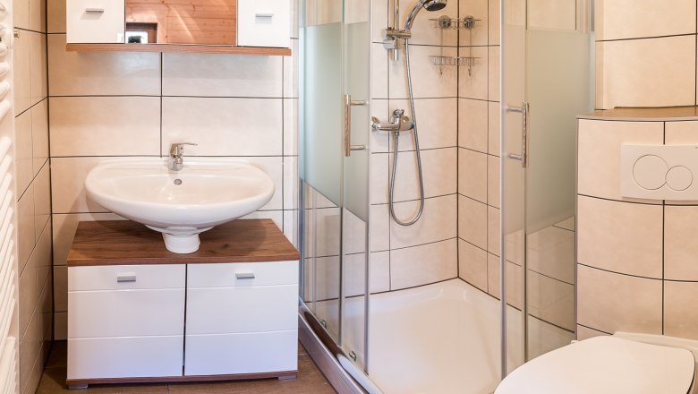 Modernes Badezimmer mit Dusche, Waschbecken, WC und blauer Badematte.