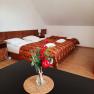 Ein gem&uuml;tliches Schlafzimmer mit zwei Betten, dekoriert mit roten Beeren in einer Vase im Vordergrund.