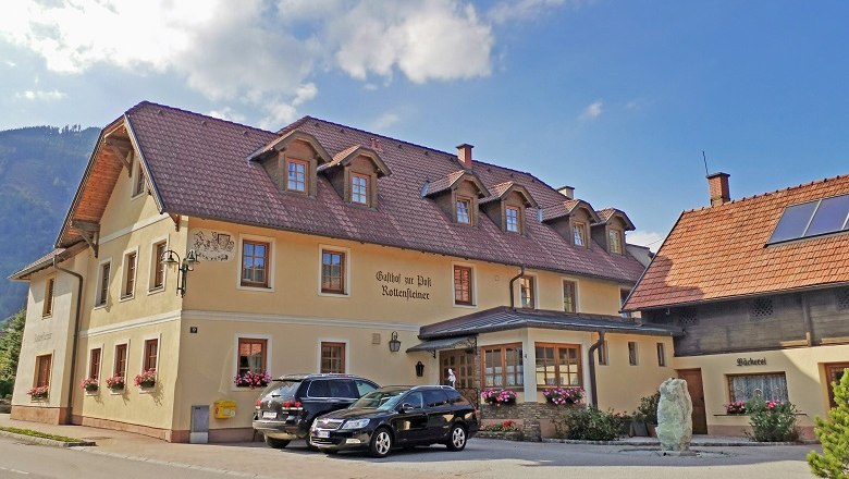 Ein traditionelles Gasthaus mit B&auml;ckerei und geparkten Autos davor.