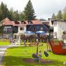 Ein Gasthof in den Alpen mit Spielplatz und Menschen im Freien.