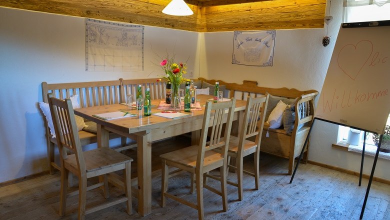 Gemütlicher Seminarraum mit Holztisch, Stühlen und Flipchart.