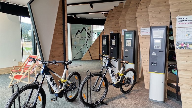 Innenansicht eines E-MTB Verleihs mit Fahrr&auml;dern und Ticketautomaten.