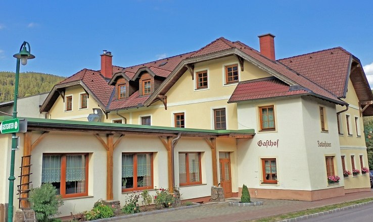 Ein traditioneller Gasthof mit gelber Fassade und roten Dächern.