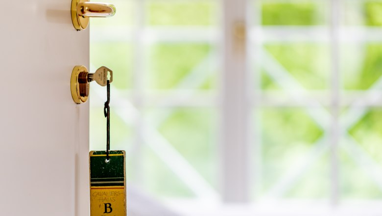 Ein Schlüssel steckt in einer Tür mit einem Anhänger, auf dem "Kavaliershaus B Burg Feistritz" steht.