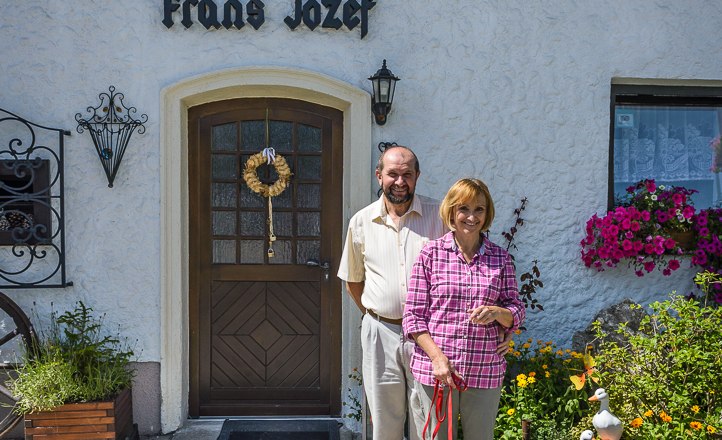 Ein Paar steht vor dem G&auml;stehaus Frans Jozef mit einem Hund auf dem Gehweg.