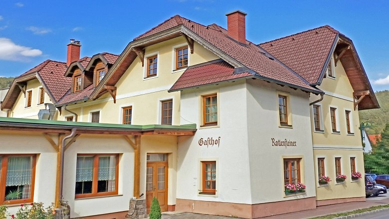 Ein traditioneller Gasthof mit mehreren Stockwerken und roten Dachziegeln.