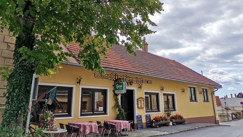 Außenansicht eines traditionellen Gasthauses mit gelber Fassade und roten Dachziegeln.