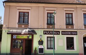 Fassade einer Pizzeria mit dem Namen Maestro Nino in einem zweistöckigen Gebäude.