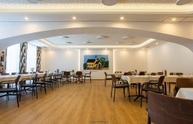 Innenansicht eines modernen Wirtshauses mit gedeckten Tischen und einem Wandgemälde.