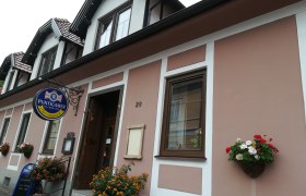 Au&szlig;enansicht eines Geb&auml;udes mit Schild 'Puntigamer' und Blumendekoration.