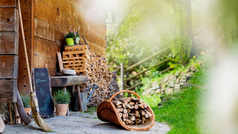 Dekorative Gegenst&auml;nde auf Steinboden neben einer Holzwand und einem Holzsto&szlig;.