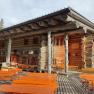 Holzhütte mit Terrasse und Bänken im Freien.