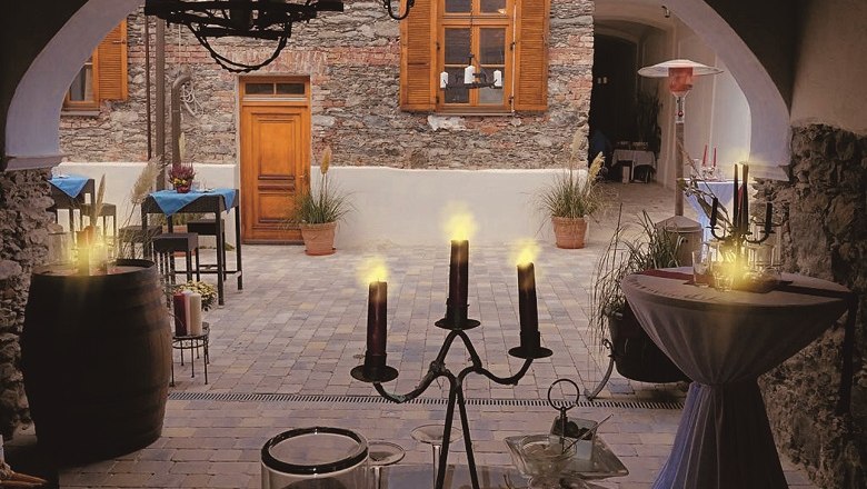 Gemütlicher Innenhof eines Cafés mit Kerzenlicht und rustikaler Steinmauer.