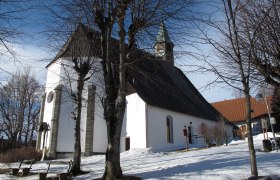 Pfarrkirche Maria Namen im Winter mit schneebedecktem Boden und kahlen B&auml;umen.