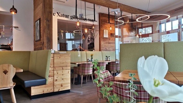 Innenansicht einer gem&uuml;tlichen B&auml;ckerei mit Holzm&ouml;beln und modernen Leuchten.