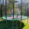 Drei Kinder springen auf einem Trampolin im Freien.