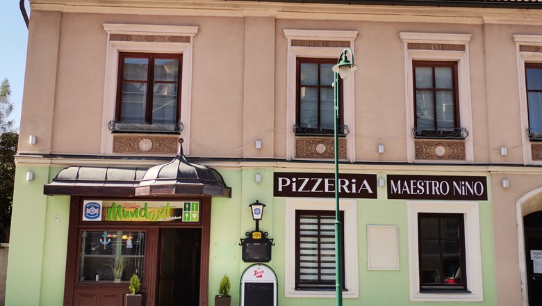 Fassade einer Pizzeria mit dem Namen Maestro Nino in einem zweistöckigen Gebäude.