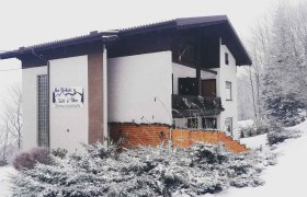 Ein verschneites Gebäude mit einem Schild 'Bei Webels Ski & Bike Zimmer-Apartments'.