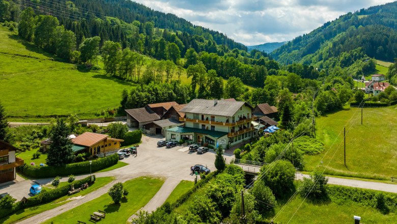 L&auml;ndliche Landschaft mit einem gro&szlig;en Geb&auml;ude, umgeben von gr&uuml;nen H&uuml;geln und B&auml;umen.